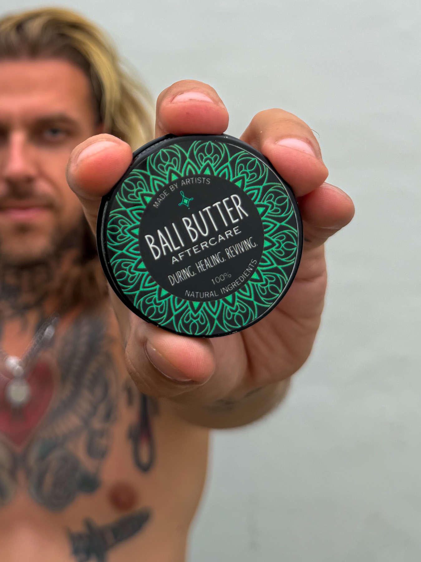 Tattoo artist presenting a Bali Butter aftercare tin